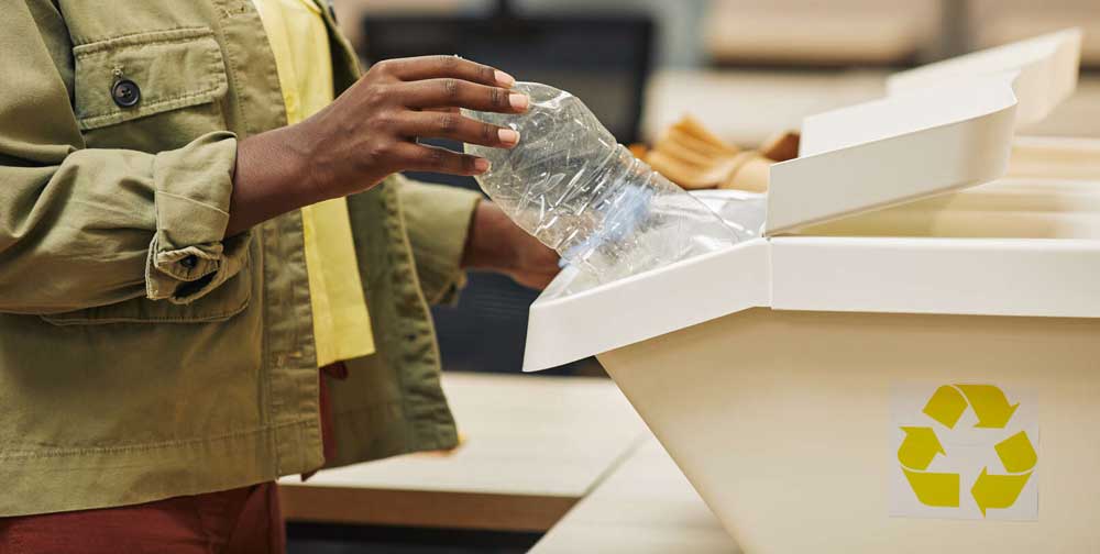 Woman putting plastic bottle into waste sorting bin